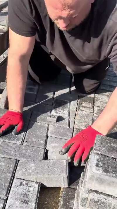 Stone mason breaks bricks into perfect shapes to fit into the gaps of this walkway
